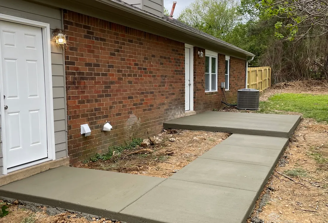 New concrete pad and walkway at the side of a brick home