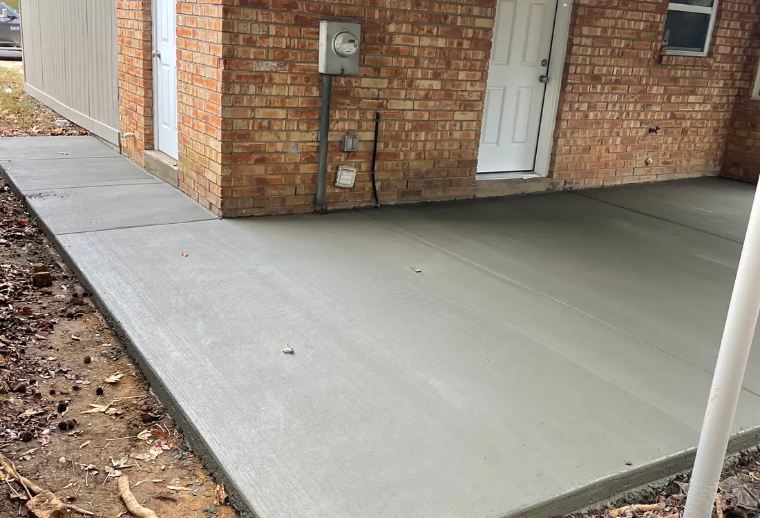Concrete walkway and porch pad beside a brick home