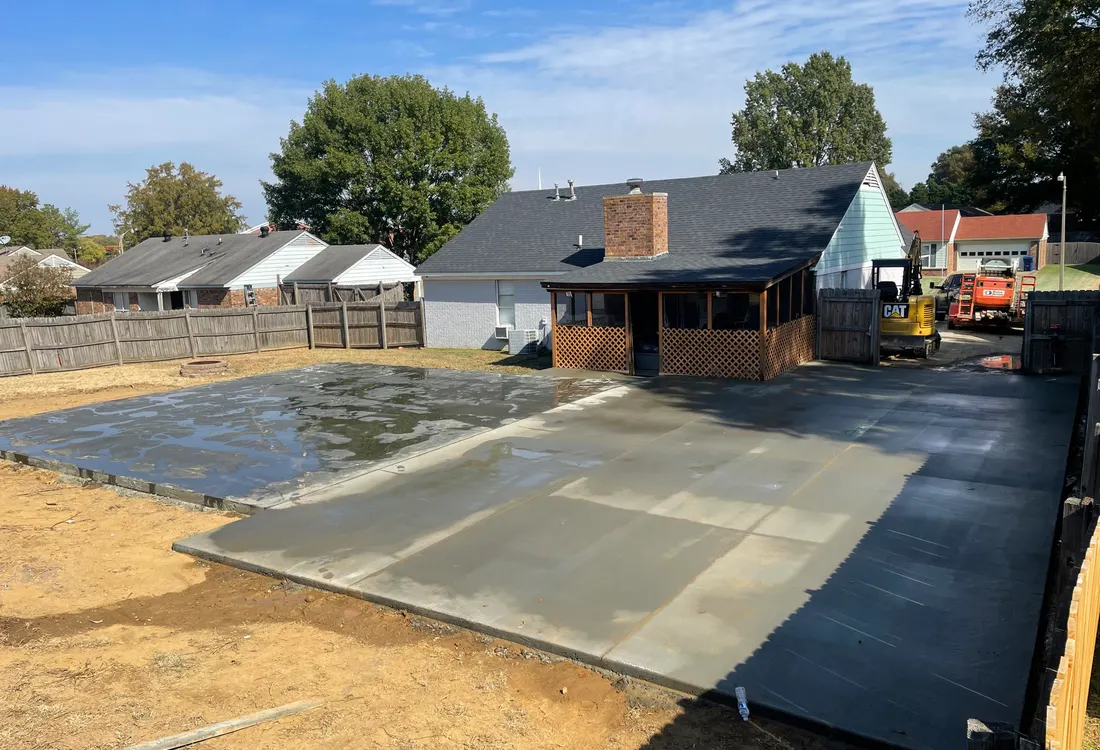 Crew pouring and screeding a large concrete surface