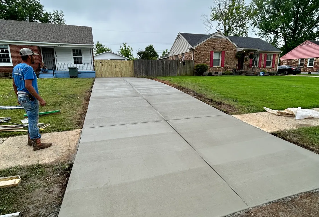 New concrete driveway with a worker walking the finished slab