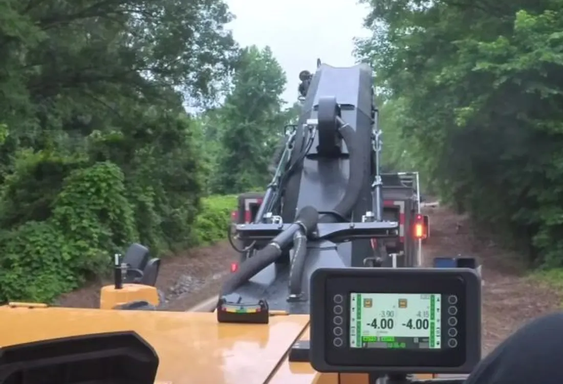 Reclaiming machine working a road surface with dust rising