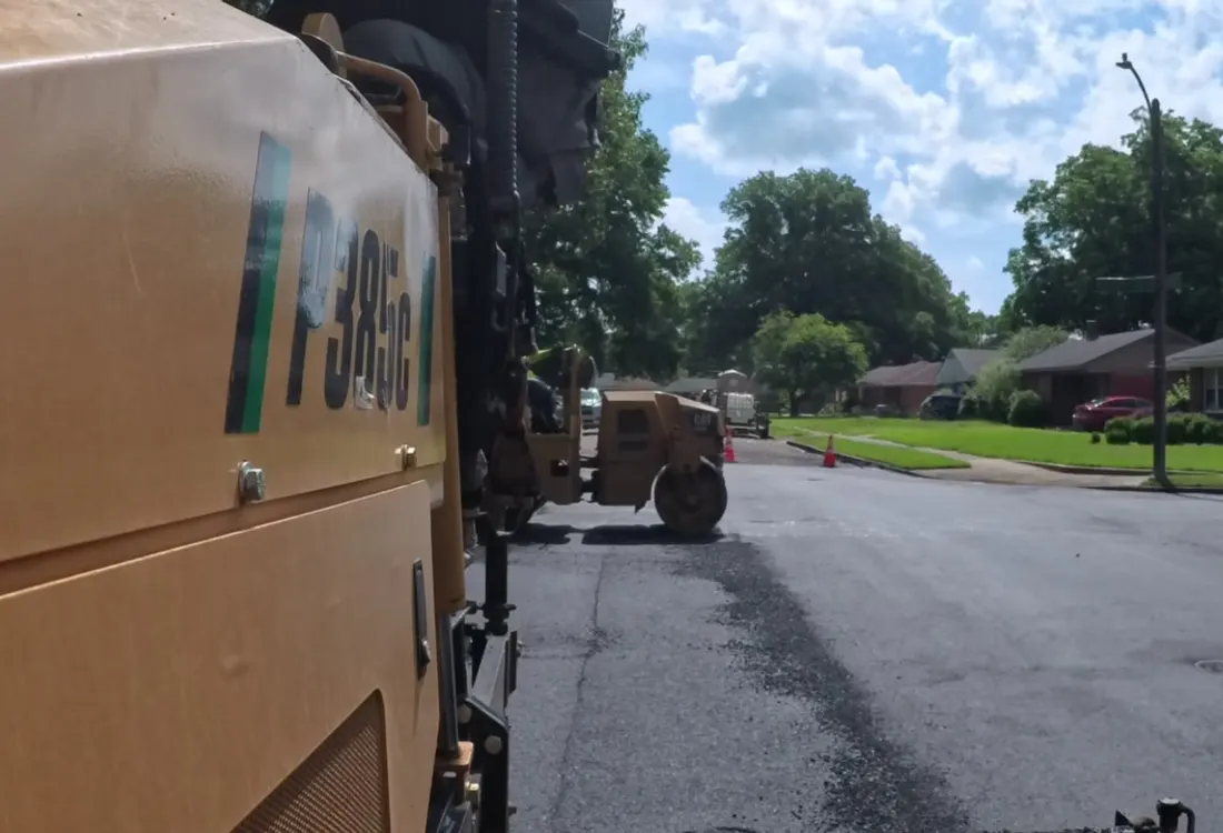Fresh asphalt mat laid on a residential street beside the paver