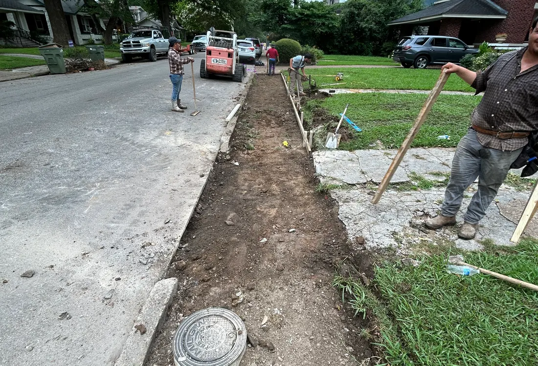 Crew preparing a street-side sidewalk section for replacement